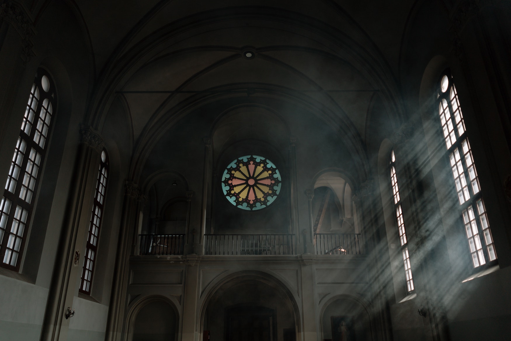 Sunlight shining into a dimly lit church with a stained glass window